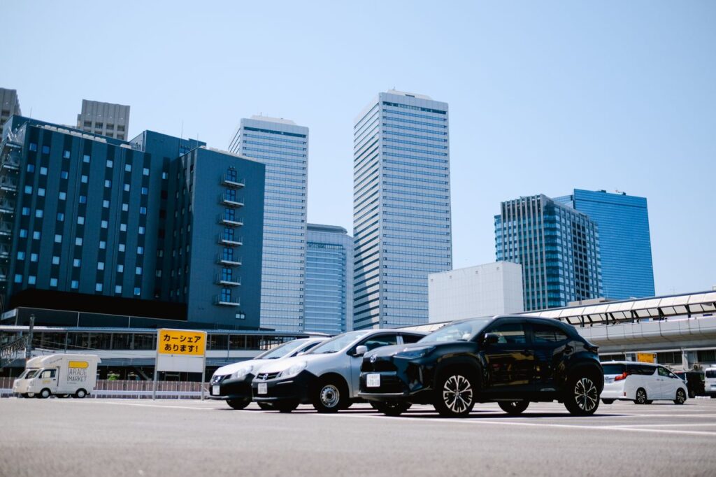 City parking lot with modern buildings and parked cars under a clear sky.